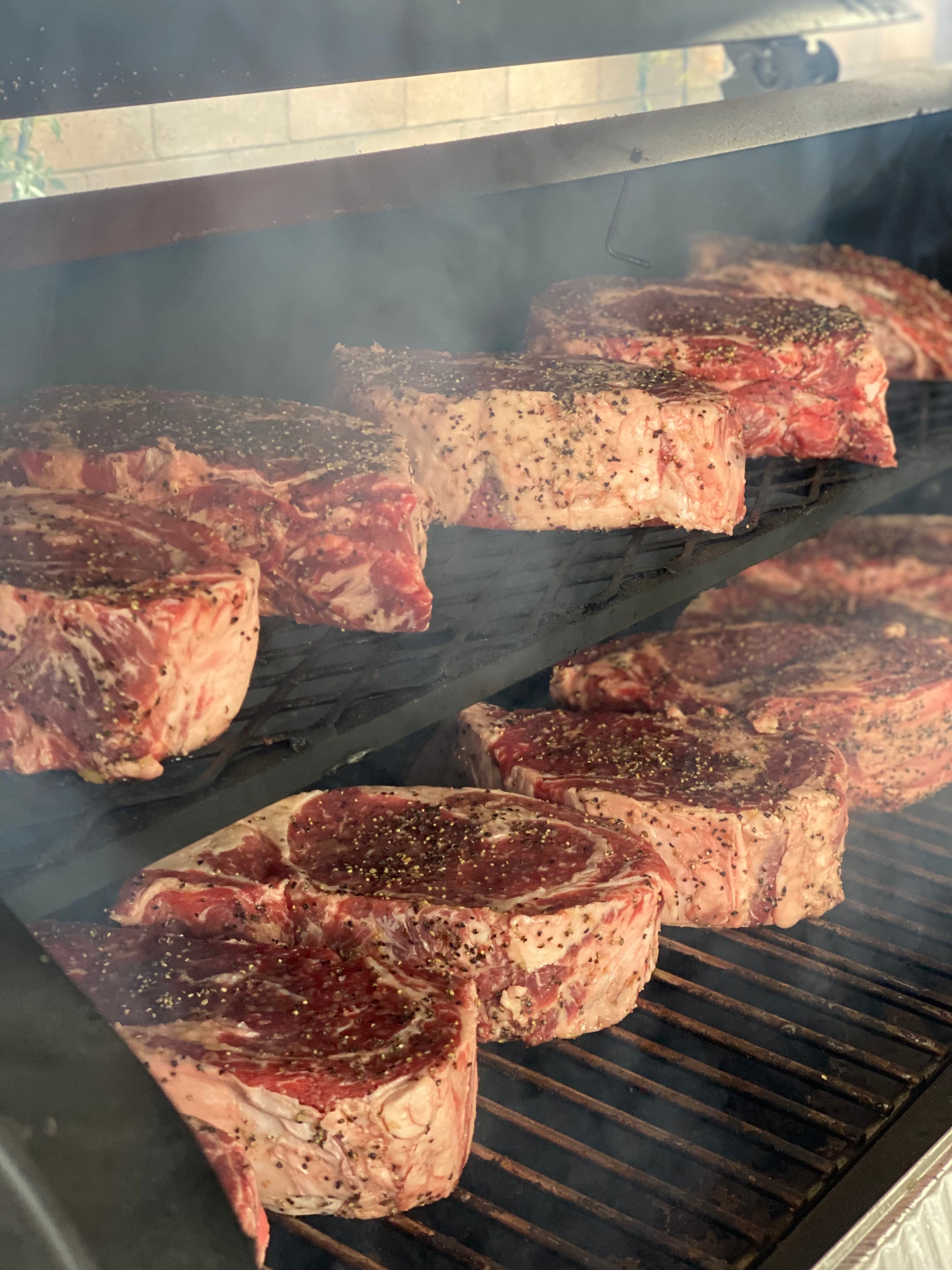 Steaks cooking on an outdoor grill seasoned with BuffalowBBQ Signature BBQ Rub.